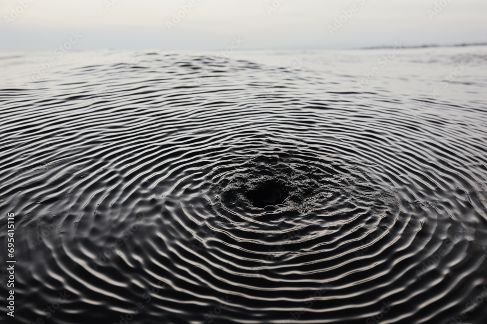 Aufkleber an abstract fingerprint silhouette against a backdrop of rippling water texture.