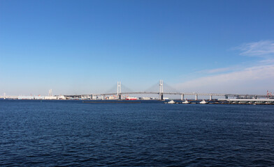 Fototapeta na wymiar 遠くに横浜ベイブリッジが見える風景　雲がほとんど無い青空、青い海にかかる橋