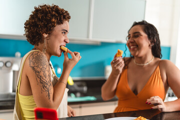 Young women in the kitchen eating tapioca dice, a traditional snack from Brazil.