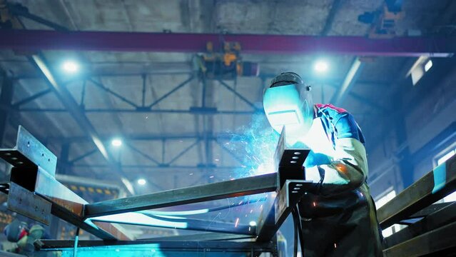 Professional Welder Working at factory facility. Factory workshop with a male technician welding in it