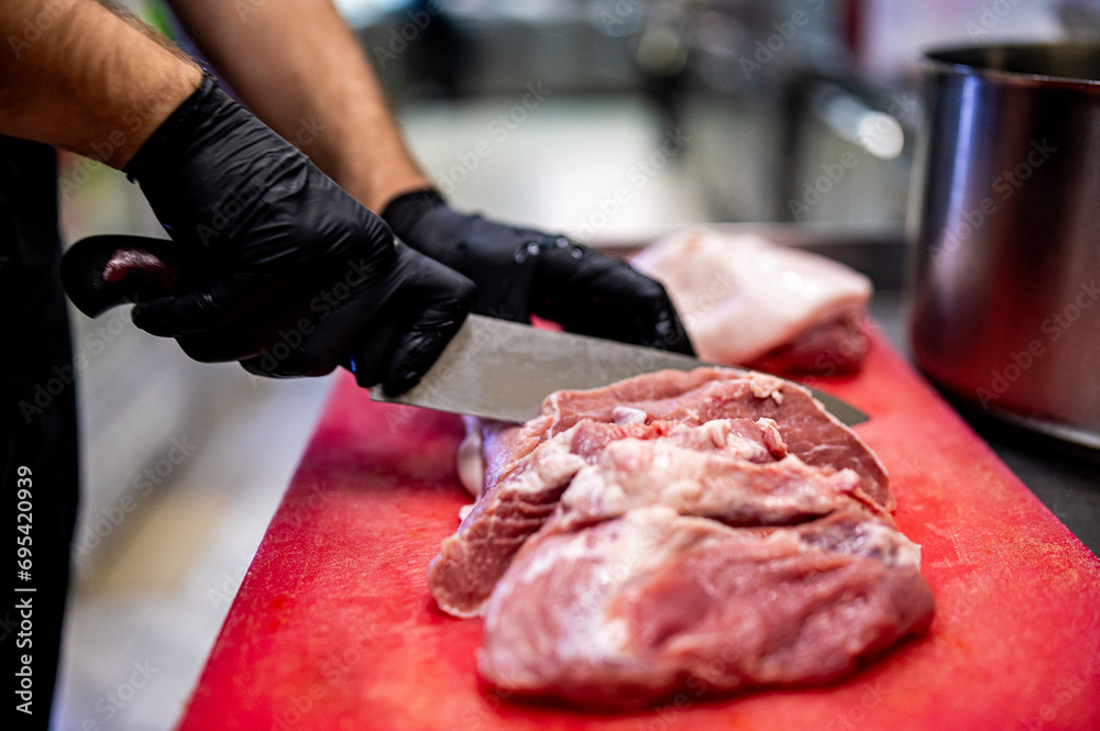 Wall mural chef butcher cutting beef meat with knife on kitchen