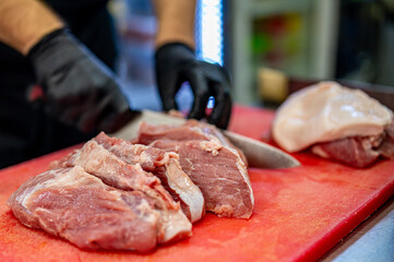 Chef Butcher cutting beef meat with knife on kitchen