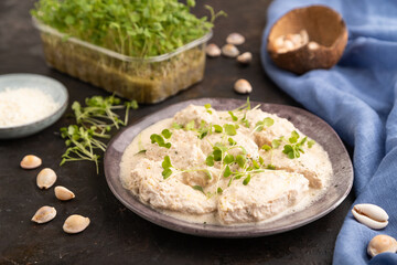 Stewed chicken fillets with coconut milk sauce and rucola microgreen. side view, selective focus.