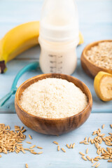 Powdered milk and oatmeal, banana baby food mix, on blue wooden, side view, selective focus