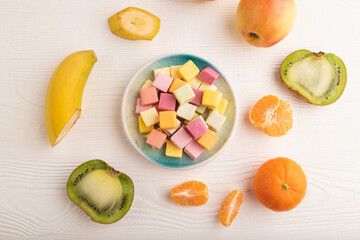 Various fruit jelly chewing candies on white wooden. apple, banana, tangerine, top view.