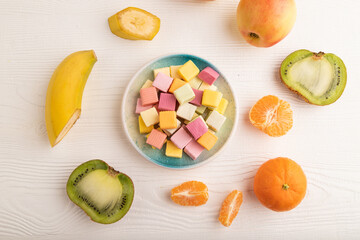 Various fruit jelly chewing candies on white wooden. apple, banana, tangerine, top view.