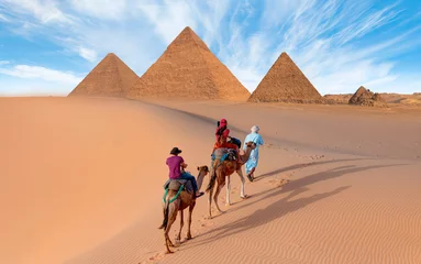 Foto auf Acrylglas Camels in Giza Pyramid Complex - A woman in a red turban riding a camel across the thin sand dunes - Cairo, Egypt © muratart