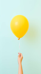 Hand holding a yellow balloon over pastel blue background. Generative AI.