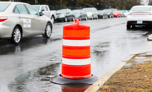 orange street construction cone on road with blurred background, symbolizing caution and ongoing work, in a stock photo