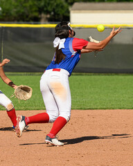 Girls softball players making athletic plays, throwing, sliding and catching the ball during a game