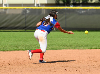 Girls softball players making athletic plays, throwing, sliding and catching the ball during a game