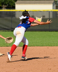Girls softball players making athletic plays, throwing, sliding and catching the ball during a game
