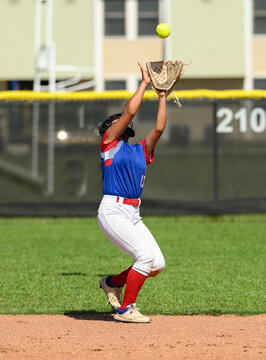 Girls softball players making athletic plays, throwing, sliding and catching the ball during a game