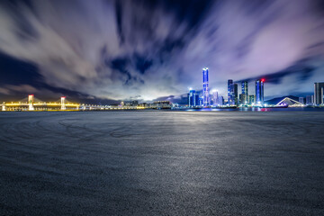 Asphalt road square and city skyline with modern buildings at night - obrazy, fototapety, plakaty