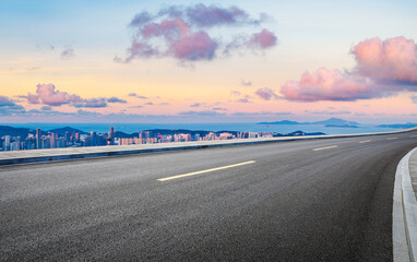 Asphalt road and beautiful coastline with modern buildings at sunset. High Angle view.