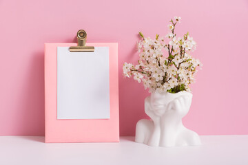 Empty sheet paper with head shape vase with spring bloom flowers on pink background