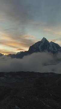 Taboche and Cholatse Mountain at Colorful Sunset. Himalaya, Nepal. Aerial View. Drone Flies Backwards. Vertical Video