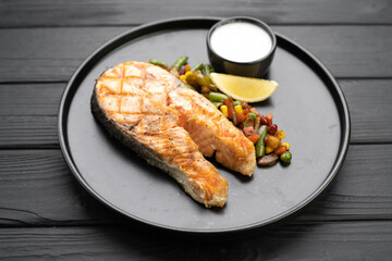 Healthy seafood food. Fresh cooked delicious salmon steak with vegetables and sauce baked on a grill.