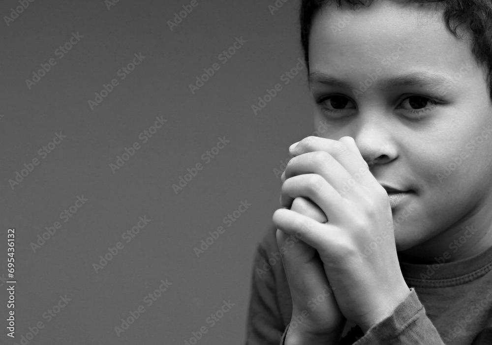 Wall mural little boy praying to God with hands together with people stock image stock photo