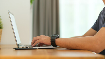 Handsome young asian man working online with laptop computer at modern home office.