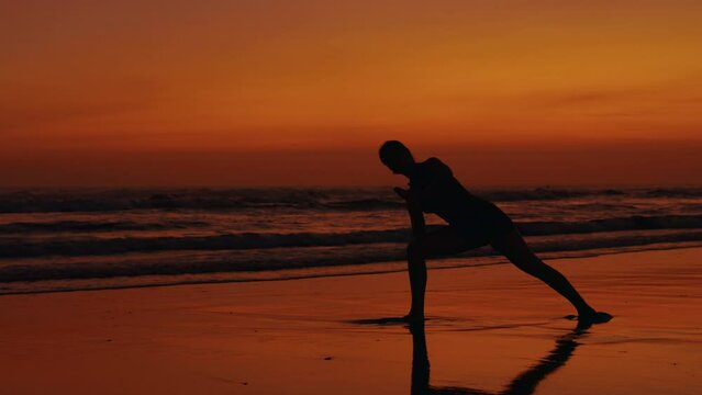 Silhouette of Sporty Woman Doing Yoga Outdoors at Sunset. Slim Girl Is Training on the Seashore. Athletic Woman Stretching Outside. Yoga and People Concept
