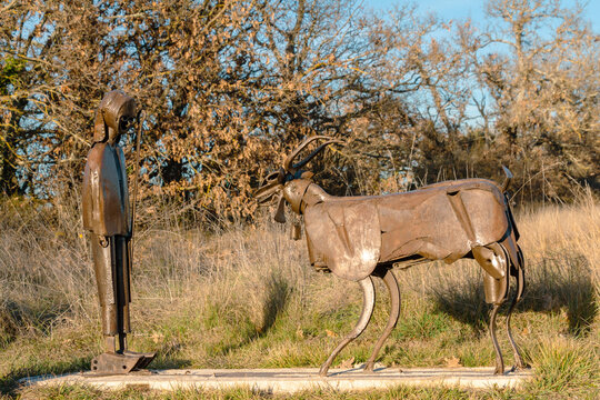 Lussan, Gard, France, January 1 2022 : land art, metallic sculpture of a shepherdess and a goat on display in nature. Artist : Guy Michel Born.
