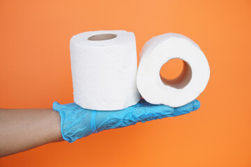 Close up hand hold two rolls of white tissue paper, isolated on orange background.Concept, cleaning tool, hygienic to wipe dirty and absorb wet ,use tissue paper for hygienic and sanitary.Toilet paper