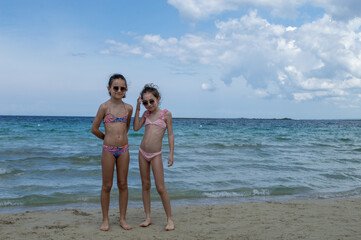 Ritratto di due sorelle gemelle di nove anni al mare in spiaggia.