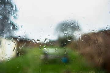 Water droplets on a window with an out of focus garden beyond