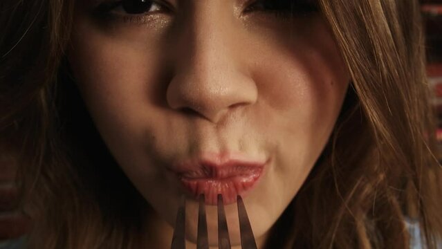 Close up shot of person eating different tasty food. View from a fork, girl puts slice of broccoli on a fork inside mouth, looks at camera. POV.