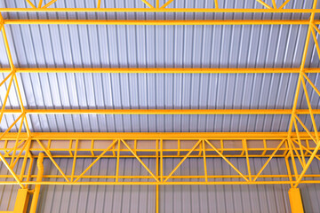 Yellow metal roof beams structure and aluminum corrugated tile roof of industrial warehouse...