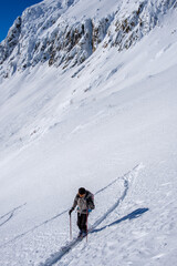 Fototapeta na wymiar Scialpinista sale lungo un pendio innevato in Canton Ticino, Svizzera
