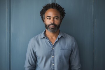 Obraz premium Portrait of a glad afro-american man in his 40s sporting a versatile denim shirt against a bare monochromatic room. AI Generation