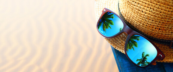abstract tropical sand beach from above with straw bucket hat and sunglasses, palm trees...