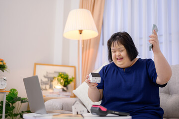 Asian woman with Down syndrome Happy shopping online on buying a house with a credit card....