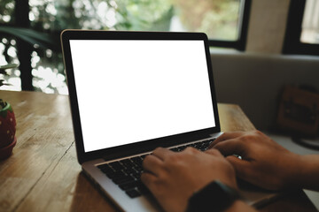 Mockup image of hand using laptop with blank white screen on vintage wooden table near glass...