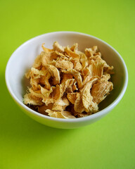 There is a white plate with pieces of dried ginger on a green background. side view. spice preparation of specialties.