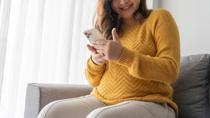 Pregnant asian woman holding smartphone at home using mobile app for pregnant women