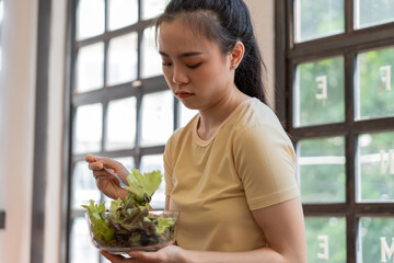 Unhappy Asian girl eating green vegetables salad upset bored of dieting. anorexia Bored  Woman...