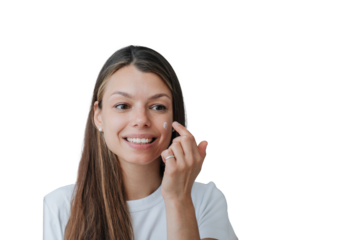 Close up portrait of pretty Italian young woman with long loose hair standing against transparent background puts skin cream on face broad smiles satisfied by skin care products