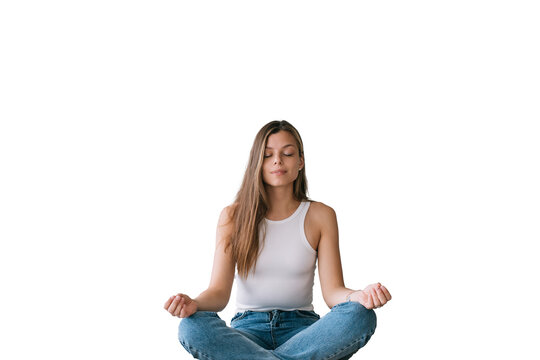 Focused young adult caucasian woman in white t-shirt sitting on bed in yoga meditation pose eyes closed against transparent background. Confident Hispanic female makes breath exercise at home.