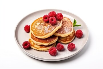  a white plate topped with pancakes covered in raspberries and topped with powdered sugar and topped with fresh raspberries on top of the plate, on a white background.