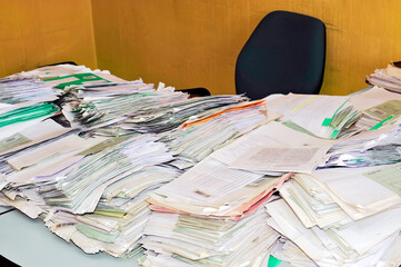 Desk in the office with stacks of paperwork. 