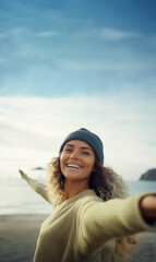 Young afro American woman with curly hair  taking selfie shot with arms outstretched in freedom and wellbeing concept, at the beach