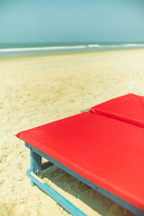 a pair of red sun loungers on a sandy sea beach