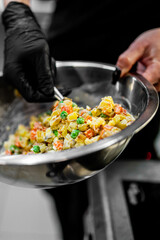 Professional chef cooking Salad Olivier in restaurant kitchen