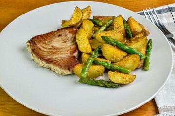 tuna steak  served with  potato wedges and asparagus