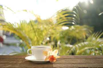 Coffee cup and orchid flower on table at balcony