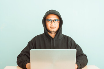 A hacker wearing a hoodie and goggles is hacking into his victims' financial systems. Gray...