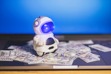 Real robot with dollars money on laptop. Modern digital technology concept. Artificial intelligence...